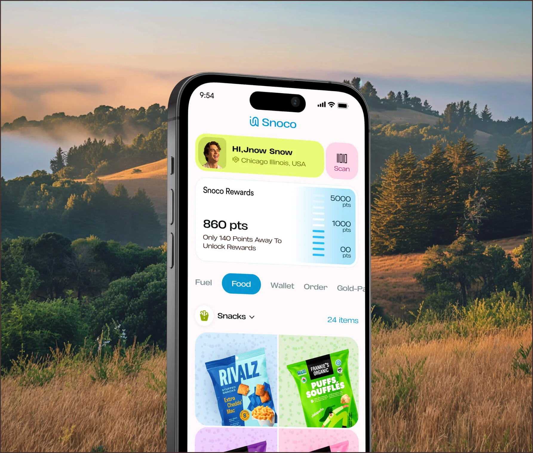 Phone showing a snack rewards app over hills at sunset