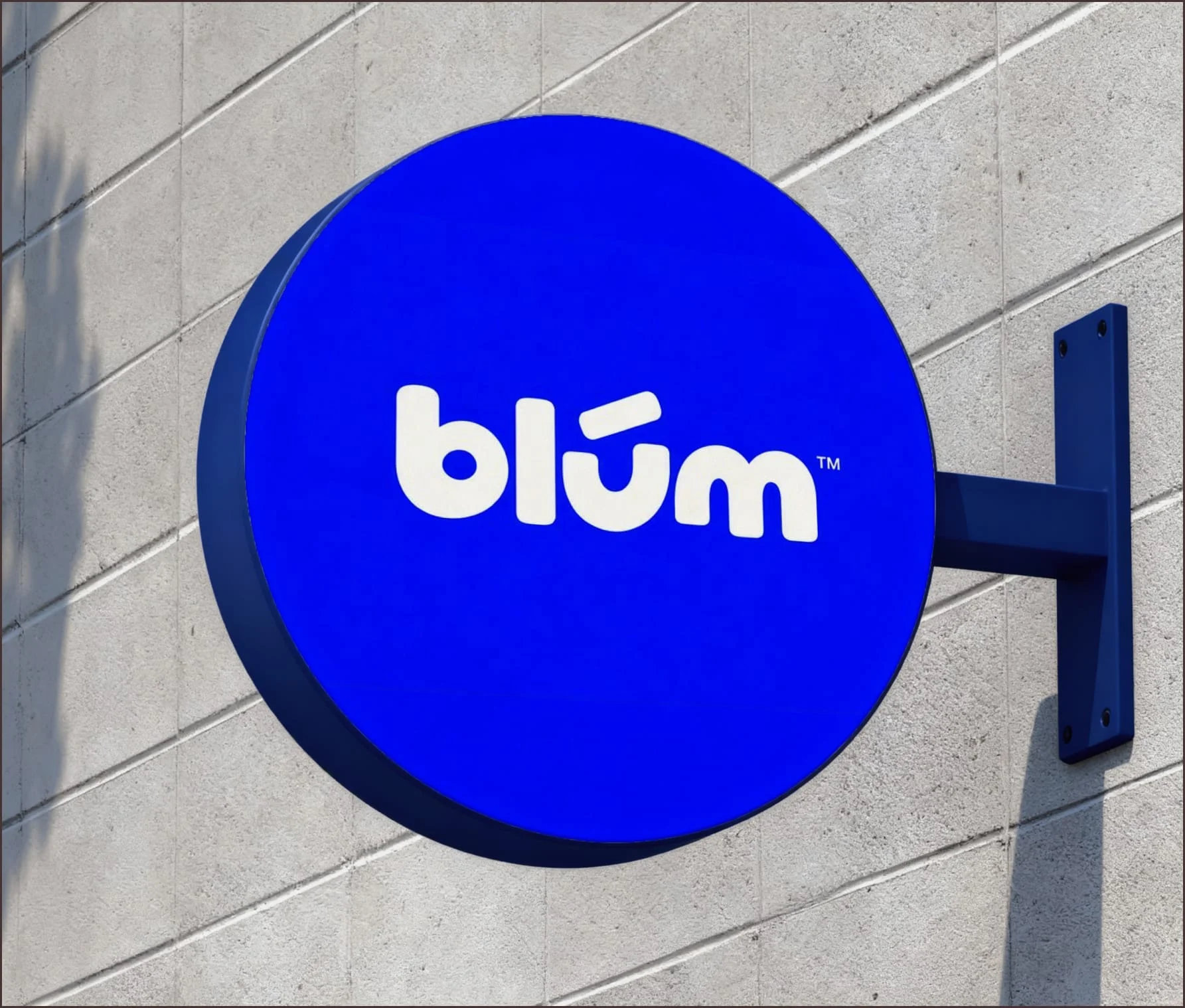Blum logo on a round blue sign mounted on a brick wall